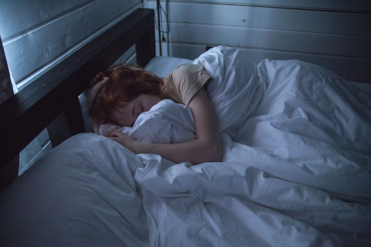 Person sleeping under white bedding in a cool bedroom